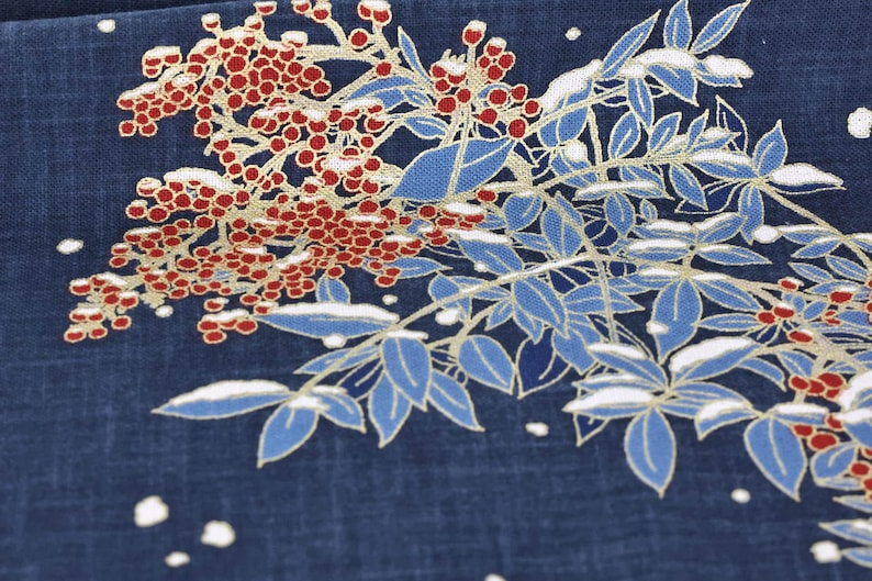 May include: Close-up of a navy blue fabric with a floral design. The design features red berries, blue leaves, and white accents, possibly depicting a winter scene. The leaves have gold outlines.