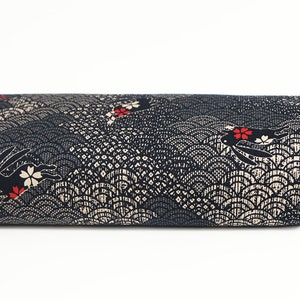 May include: Black fabric with a repeating pattern of white waves and black rabbits with red flowers.