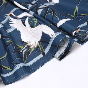 Könnte beinhalten: Blauer Stoff mit einem weißen Kranichmuster. Der Stoff hat einen weißen Rand mit einem blauen Streifen. Der Kranich ist ein traditionelles japanisches Symbol für Glück und Langlebigkeit.