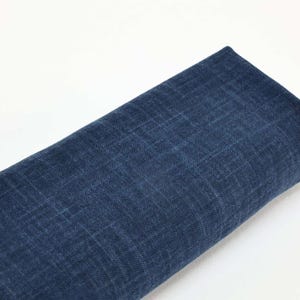 Peut inclure: Un morceau de tissu en denim bleu foncé enroulé. Le tissu a un aspect texturé avec des motifs de tissage diagonaux et horizontaux visibles. Le denim est de couleur unie, sans motifs ni dessins visibles.