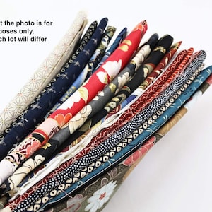 Può includere: Un mucchio di ritagli di stoffa colorati con vari motivi, tra cui disegni floreali, geometrici e astratti. Il tessuto è disposto a ventaglio, mostrando le diverse trame e colori.