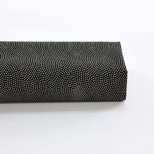 Peut inclure: Un morceau de tissu noir plié, orné d'un motif répétitif de petits points blancs cassé. Le tissu est rectangulaire et semble être roulé ou plié, le motif étant visible sur la surface supérieure. Le fond est blanc uni.