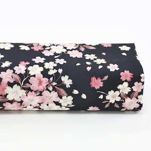 Peut inclure: Un rouleau de tissu noir orné d'un motif floral. Le motif présente des fleurs de cerisier roses et blanches avec des feuilles marron. Le tissu est adapté à la couture, au patchwork ou à d'autres projets créatifs.