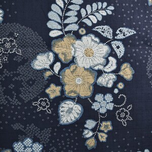 May include: Dark navy blue fabric with a floral pattern. The design features large flowers in shades of white, tan, and light blue, along with smaller floral and dot patterns. A measuring tape is visible along the left side.
