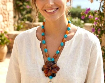 May include: A necklace featuring alternating turquoise and amber-colored beads, centered with a large, dark brown, flower-shaped pendant made of polished stones, finished with a bright turquoise tassel hanging from a gold-toned metal cap.