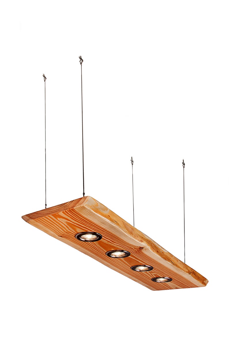 May include: A wooden pendant light fixture with four light bulbs. The fixture is made from a natural wood plank with a rough-hewn edge. The light bulbs are recessed into the wood and have a black finish.
