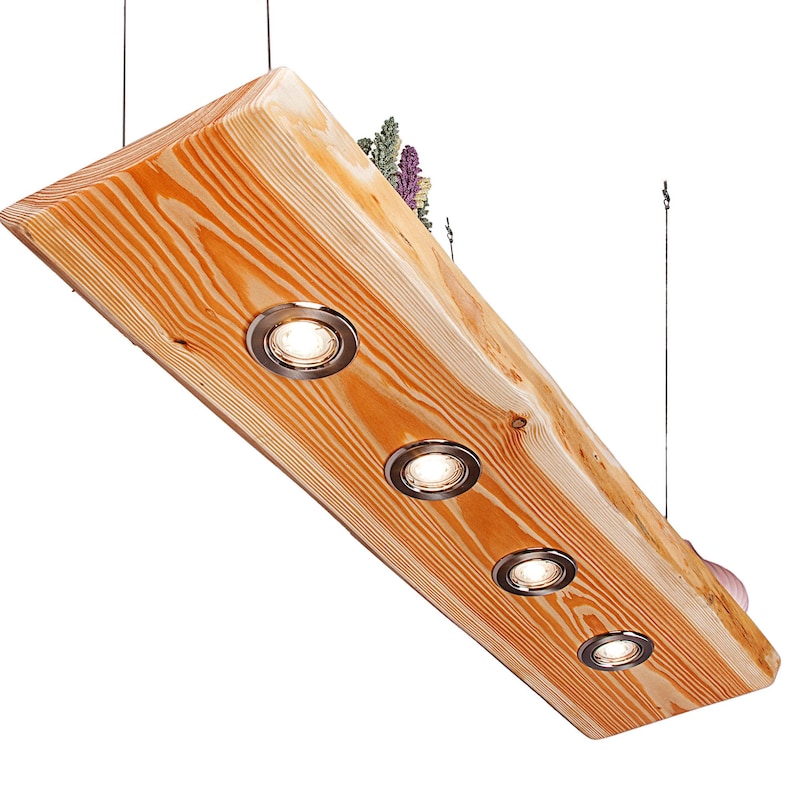 May include: A rustic wooden pendant light fixture with four integrated spotlights. The light fixture is made from a natural wood plank with a rough-hewn edge. The spotlights are recessed into the wood and have a chrome finish.
