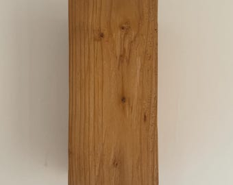 May include: A rectangular block of wood with a natural wood grain finish. The wood is a light brown color.