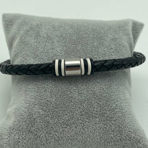 May include: A black leather bracelet with a silver and white metal accent.