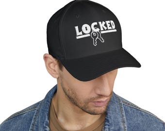 Può includere: Cappellino da baseball nero con la scritta "LOCKED" in lettere bianche e il contorno bianco di due chiavi. Il cappellino è indossato da una persona con una giacca di jeans.
