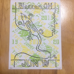 May include: A yellow and green poster with a black line drawing of a lizard. The poster says "Blossom OH Summer Tour 2019" and "Jun 19".