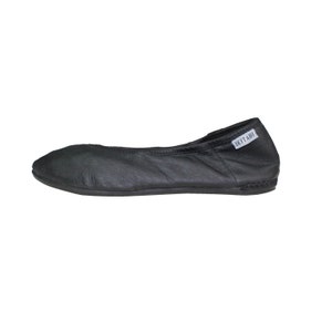 May include: Black leather ballet flat with a rounded toe. The shoe has a stitched sole and a small white tag that reads "IKITABI". The shoe is designed for comfort and flexibility.