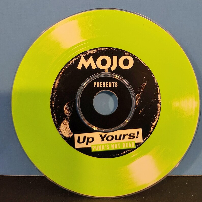 May include: A green compact disc with a black center label. The label says "Mojo Presents Up Yours! Punk's Not Dead."