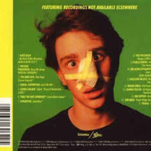 May include: A green CD case with a yellow and green background. The case features a photo of a young man with a yellow bandage over his nose. The text "Featuring recordings not available elsewhere" is printed on the case.