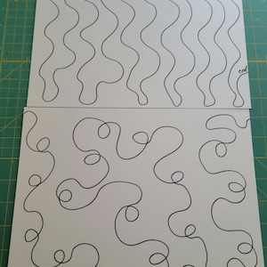 May include: Two white sheets of paper with black line drawings. The top sheet has a wavy motion design labeled "motion design" and "start" and "end". The bottom sheet has a meander loop design labeled "Meander Loop".