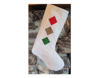 May include: A white quilted Christmas stocking with red, brown, and green diamond-shaped patches.