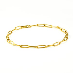 May include: A gold chain bracelet featuring a simple, linked design. The chain is made of oval-shaped links.