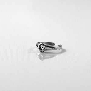 May include: A silver toe ring featuring a crescent moon and star design.