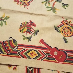 May include: A white fabric with a colorful pattern of palm trees, a donkey pulling a cart, a guitar, and a pot with a geometric design. The fabric has a red, yellow, green, and blue border.