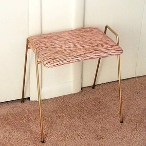 May include: A gold metal stool with a pink and white striped fabric seat.