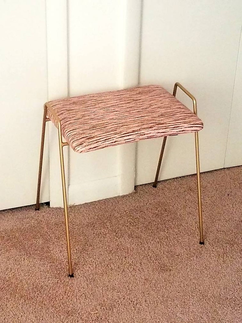May include: A gold metal stool with a pink and white striped fabric seat.