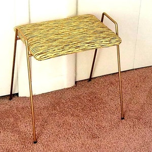 May include: A gold metal stool with a yellow and brown striped fabric seat.