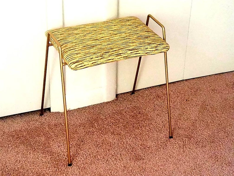 May include: A gold metal stool with a yellow and brown striped fabric seat.