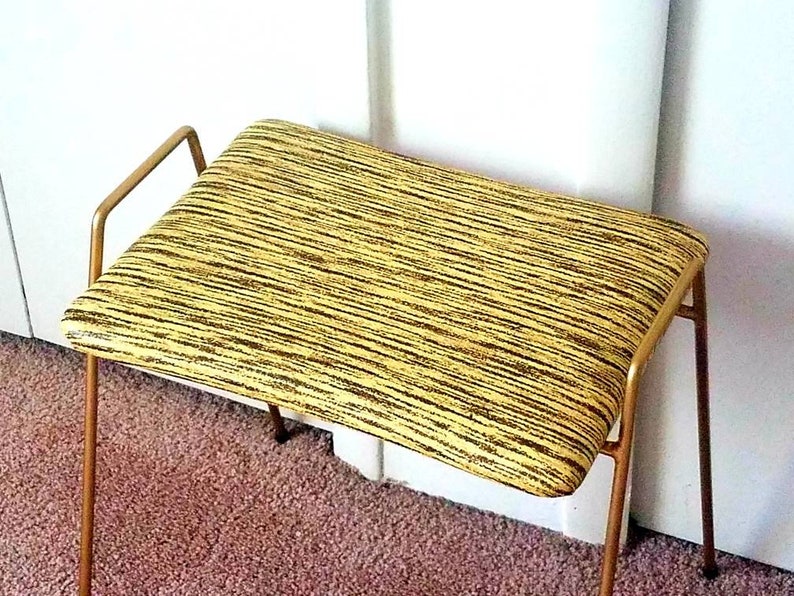 May include: A gold metal bench with a yellow and black striped upholstered seat.