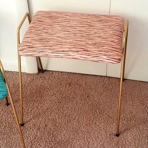 May include: A gold metal stool with a pink and white striped fabric seat.