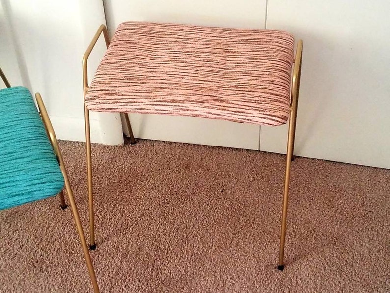 May include: A gold metal stool with a pink and white striped fabric seat.