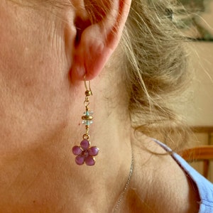 May include: Purple flower dangle earrings with clear crystal beads and gold accents.