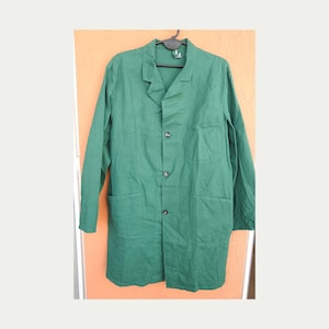 May include: A long-sleeved, forest green work coat featuring a collared neckline, a button-down front with three visible dark buttons, one chest pocket on the left side, and two large patch pockets at the waist, all hanging on a black hanger.