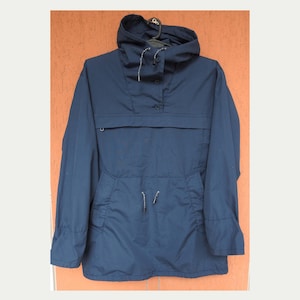 Può includere: Giacca a vento blu navy con cappuccio e tasca frontale. La giacca ha un cordoncino in vita e una chiusura con bottoni al collo. Le maniche sono lunghe e hanno polsini elasticizzati. La giacca è realizzata in materiale leggero.