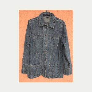 May include: A blue denim jacket with a button-up front and two pockets on the chest.