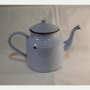 May include: A light blue enamel teapot with a lid and a curved handle. The teapot has a black trim around the lid and spout. The teapot is a vintage style and is likely used for brewing tea.