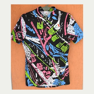 Könnte beinhalten: Schwarzes Sporttrikot mit farbenfrohem, abstraktem Design. Das Trikot hat einen halben Reißverschluss und kurze Ärmel. Das Muster umfasst rosa, grüne, blaue und weiße Pinselstriche. Das Trikot trägt den Markennamen "ULTEC" oben rechts.