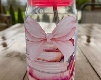 Vaso de cristal con lazo rosa y libros