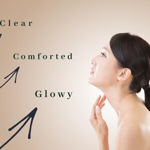May include: A woman with dark hair in a ponytail, looking upwards, with the words "Clear", "Comforted", and "Glowy" next to arrows pointing towards her face and neck. The background is a light brown color.