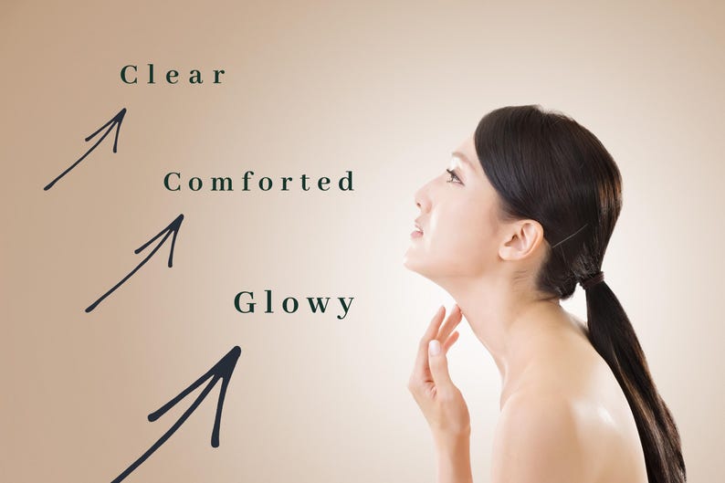 May include: A woman with dark hair in a ponytail, looking upwards, with the words "Clear", "Comforted", and "Glowy" next to arrows pointing towards her face and neck. The background is a light brown color.