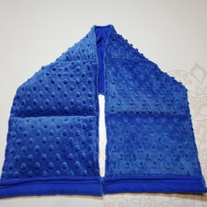 May include: A blue weighted neck wrap with a textured fabric. The wrap is divided into four sections, each with a different pattern.