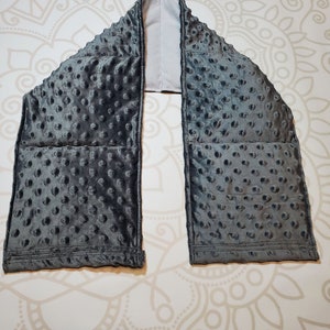 May include: Gray weighted neck wrap with a soft, textured fabric. The wrap has multiple pockets filled with weighted beads.