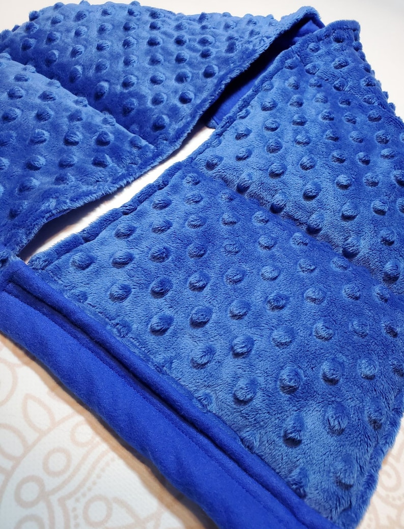 May include: A blue weighted blanket with a soft, textured surface. The blanket is folded in half and has a seam down the center.