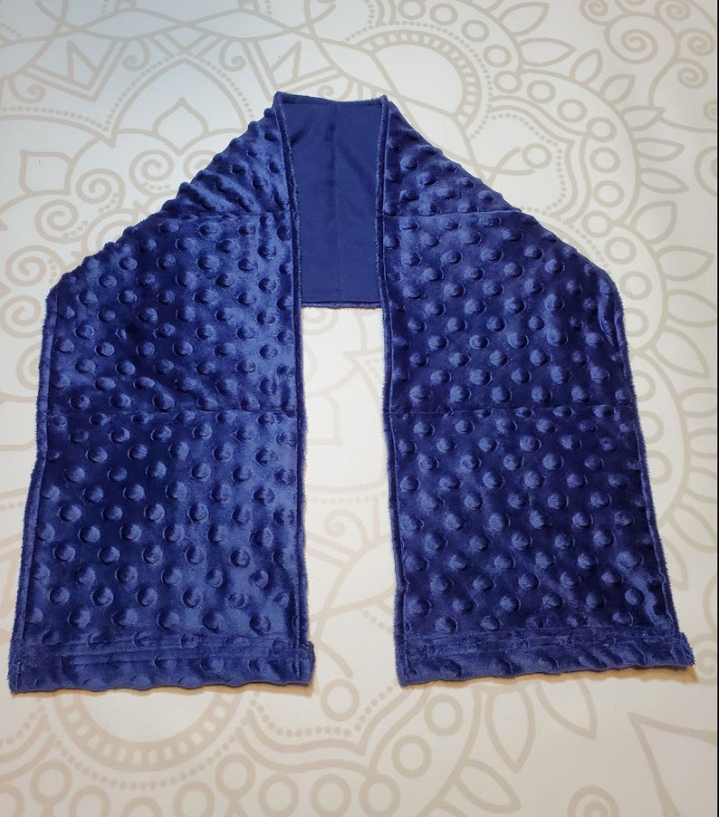 May include: A navy blue weighted sensory scarf with a soft, textured fabric. The scarf is designed with multiple sewn-in pockets filled with small, raised dots.