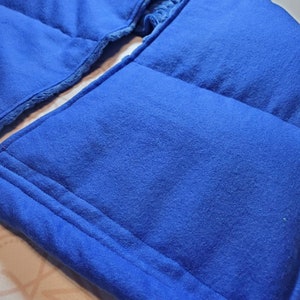May include: A blue fleece neck wrap with a soft, plush lining. The wrap is quilted with multiple compartments for added warmth and comfort.