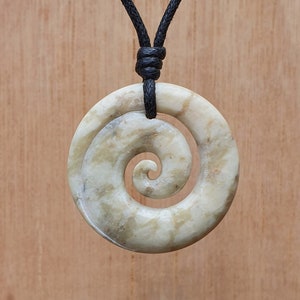 Op de afbeelding: Een witte spiraalvormige hangerketting met een zwart koord. De hanger is gemaakt van glad, gepolijst steen met een draaiend patroon.