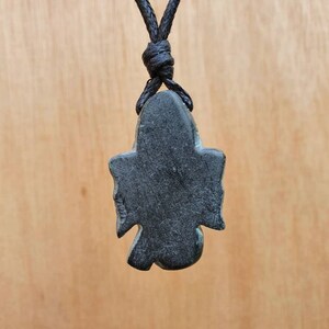 Pode incluir: Pingente de pedra preta em forma de p&aacute;ssaro com um cord&atilde;o preto.