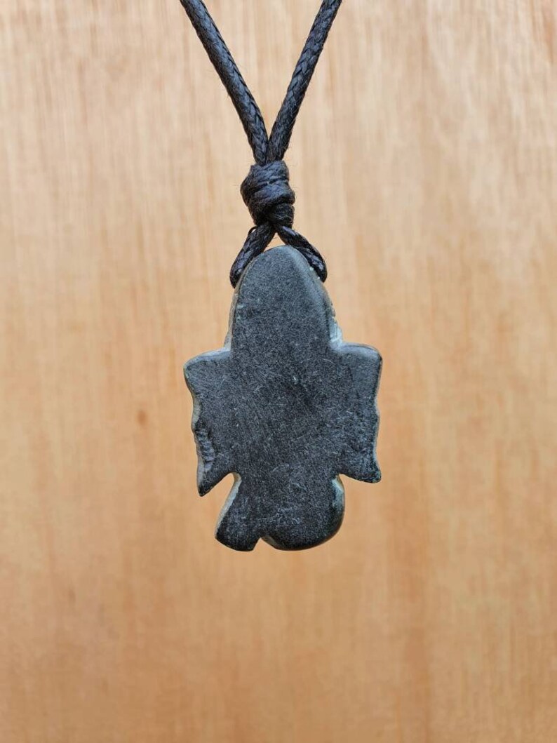 Pode incluir: Pingente de pedra preta em forma de p&aacute;ssaro com um cord&atilde;o preto.