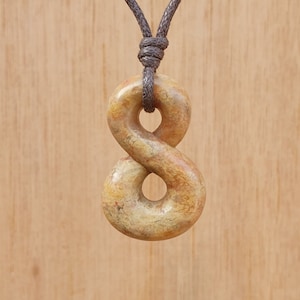 Peut inclure: Un collier en cordon marron avec un pendentif en forme d'infini de couleur brun clair, sculpté à la main.