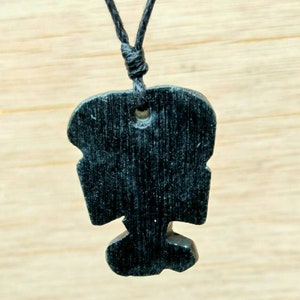 May include: A black wooden pendant with a unique design hangs from a black cord necklace.