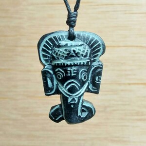 May include: Black and white carved pendant of the Hindu deity Ganesha, on a black cord necklace.